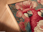 A close-up angled view shows a canvas print in a floating frame. The artwork features a tropical parrot. The piece is vintage botanical wall art. The pink coral floral bird artwork will enhance your bedroom decor.