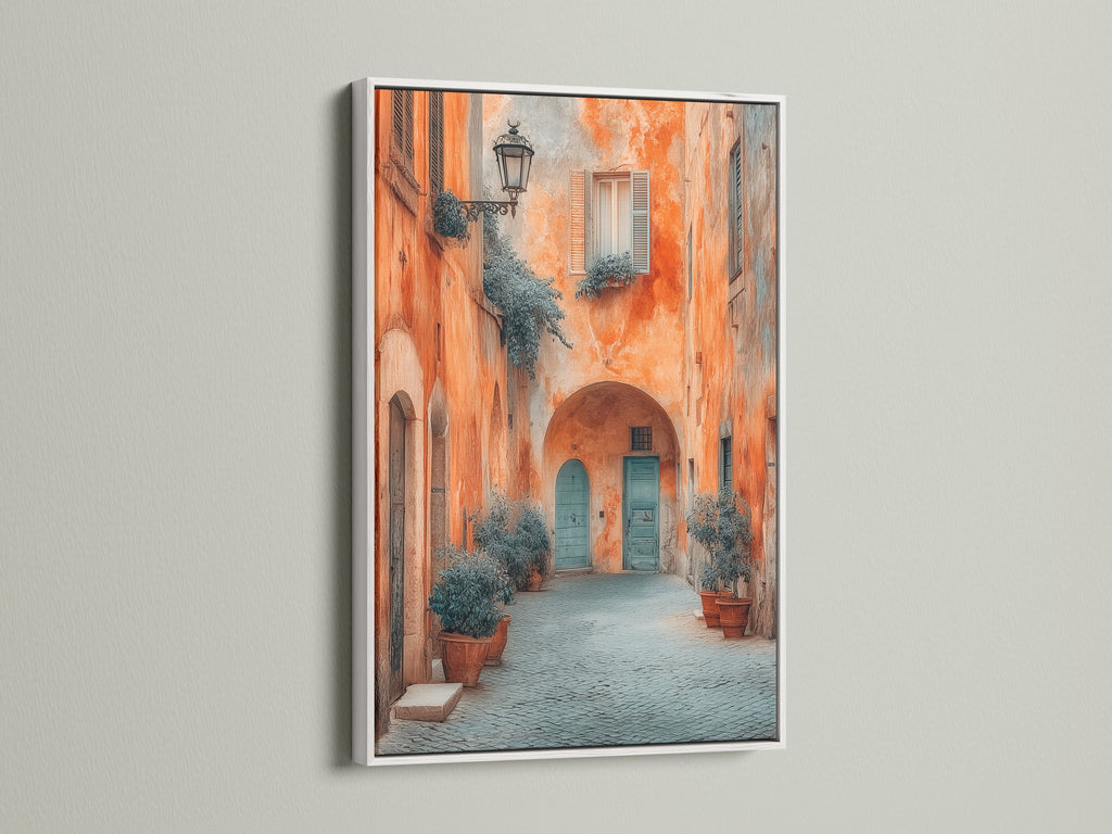 This Italian Alley Canvas Print is featured in a white frame. The European travel artwork adds style to rustic coastal or eclectic spaces. The Tuscan architecture wall art features a blue door. This fine art print would make any space beautiful