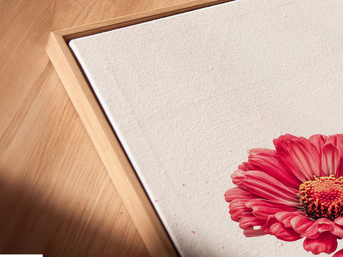 An angled close-up shows a canvas print in a floating frame. The red floral artwork appears to float. This modern flower poster is perfect for a bedroom. The crimson blossom artwork is beautifully displayed.