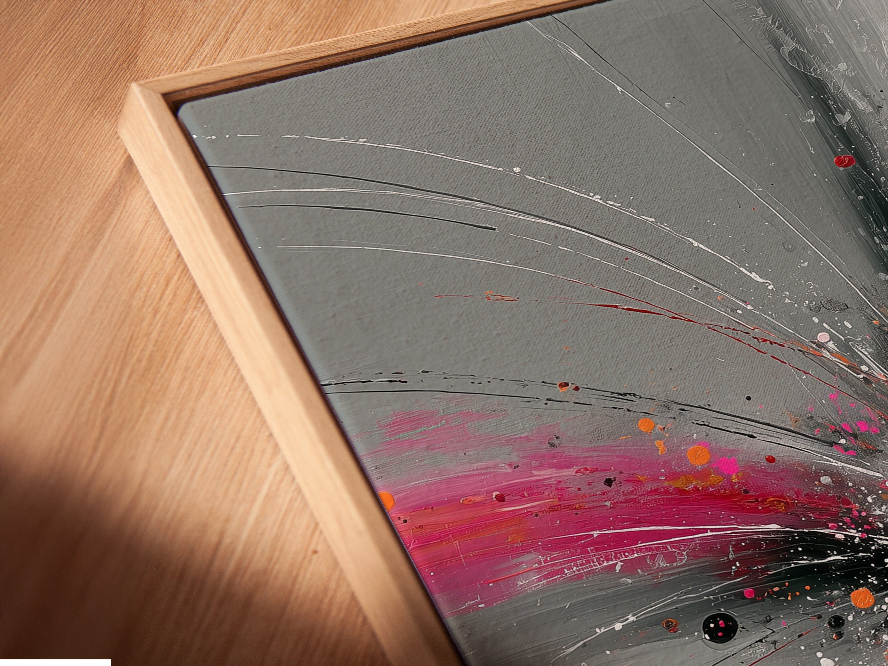 Angled close up of a canvas print featuring Abstract Burst artwork in a floating frame. The pink gray and orange hues create a dynamic modern look. Perfect for adding depth and style to your walls. This contemporary explosion print enhances any room's aesthetic. The floating frame adds sophistication.