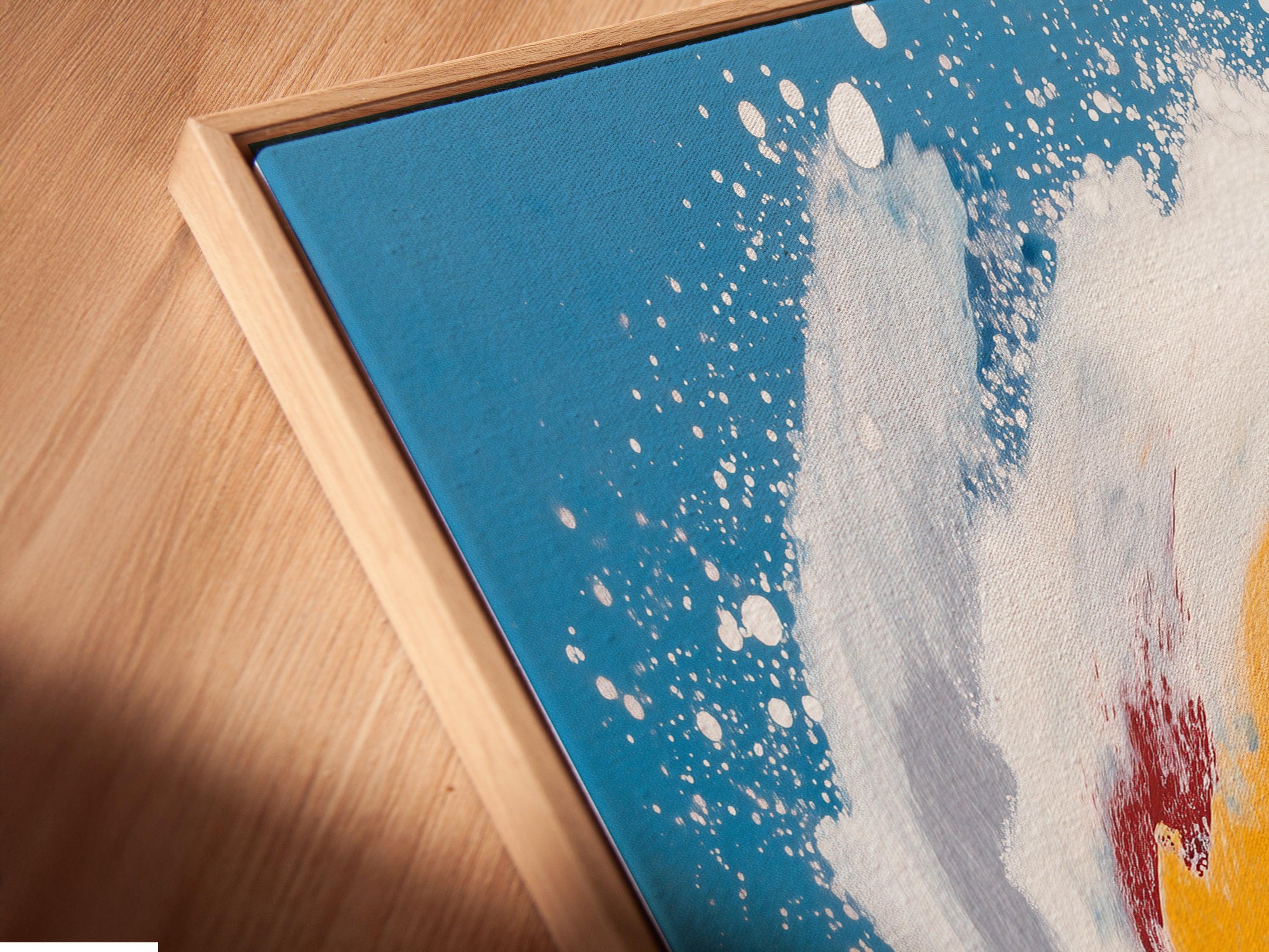A close-up of a canvas print in a floating frame. The frame enhances the abstract seascape. The teal blue artwork appears to float. This is a modern and stylish way to display coastal wall art.