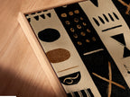 Angled close up of a canvas print in a floating frame. The artwork has black and tan stripes with tribal inspired shapes. The floating frame adds depth to the artwork. Perfect for modern minimalist homes. The Canvas enhances the artwork.