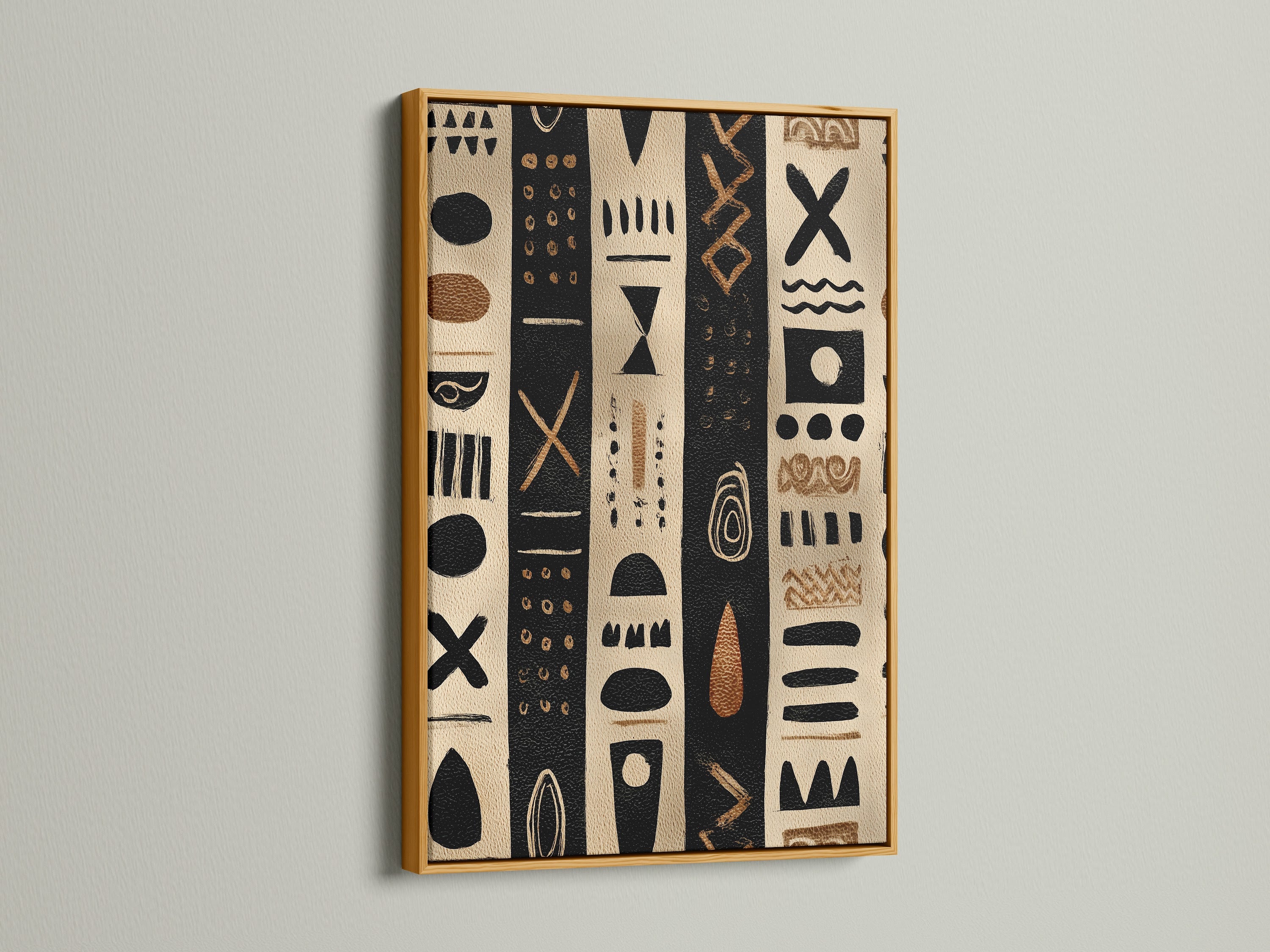 Artwork in a gold frame. The artwork has black and tan stripes with tribal inspired shapes. The artwork is hanging on a white wall. The gold frame adds a touch of luxury. This artwork is perfect for modern and classic homes.
