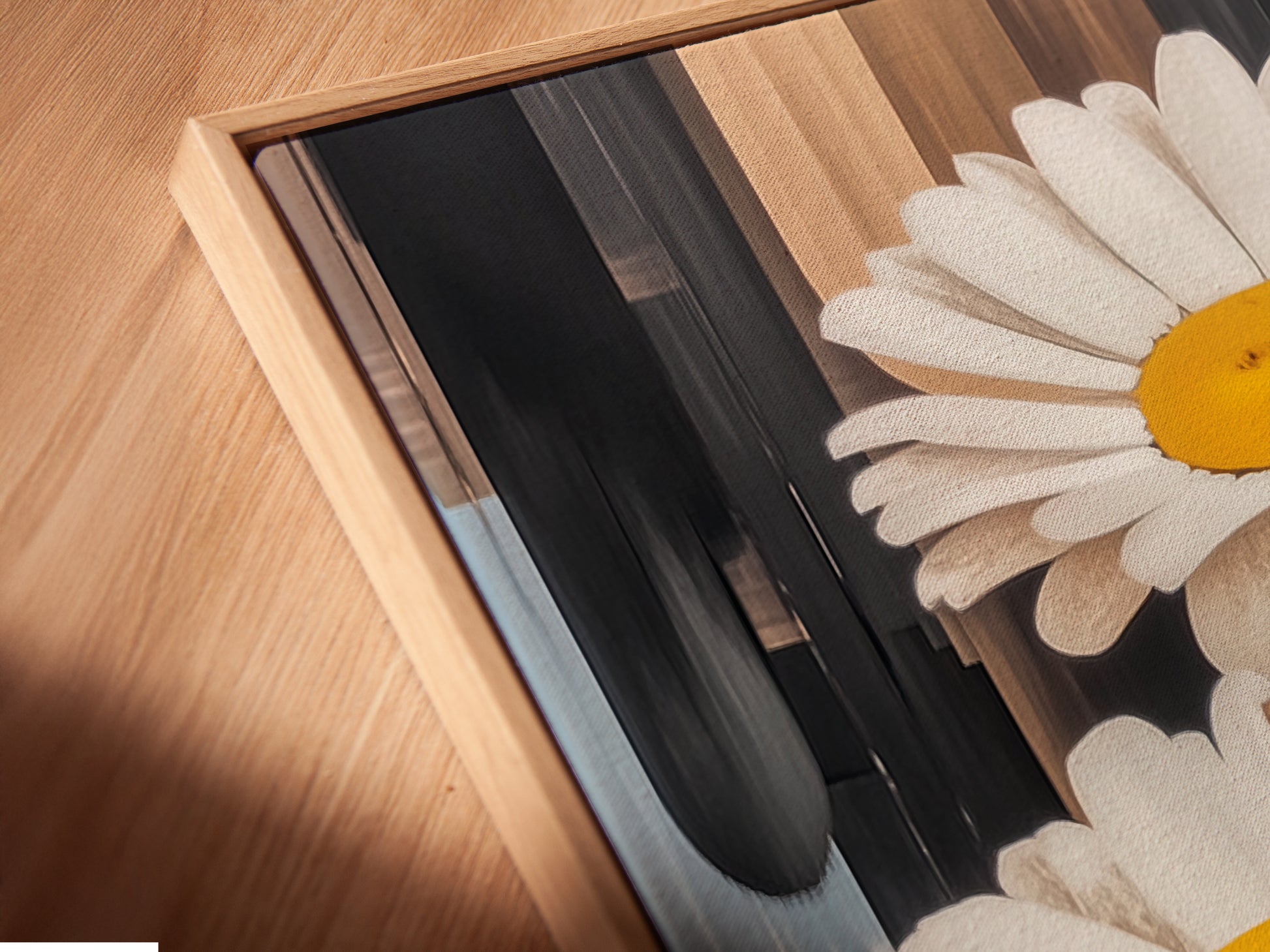 A close-up angled view of a daisy canvas print in a floating frame. The floating frame gives the artwork a sophisticated look. This modern botanical artwork is perfect for any room. The floral art enhances the wall decor.