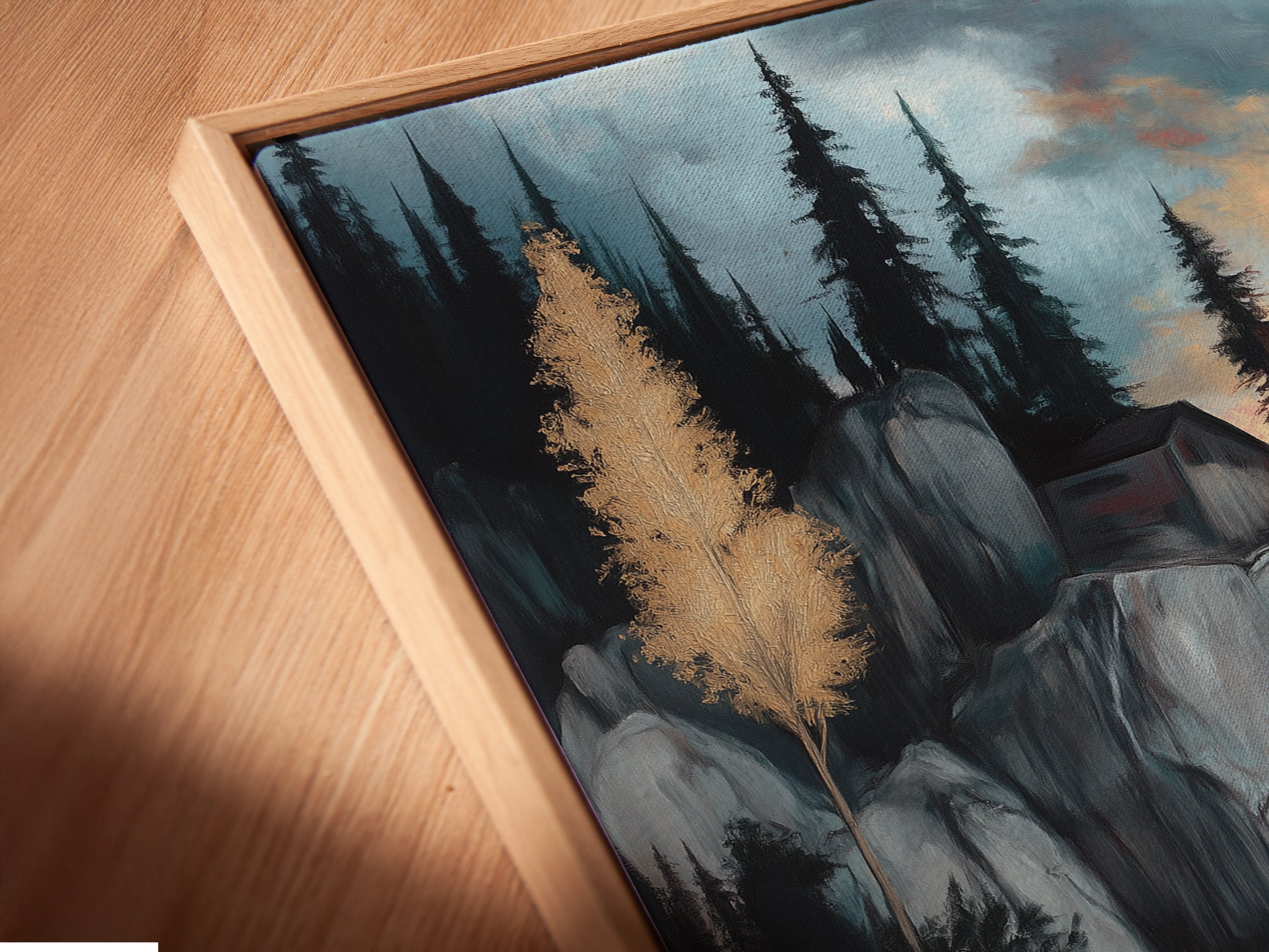 A close-up angled view of a Lakeside Cliff canvas print in a floating frame. A modern take on serene mountain artwork. Perfect for study room decor. This moody landscape features blue and gray tones. The tranquil scene shows a mountain painting and water reflection artfully combined.