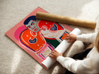 A woman carefully rolling a fine art poster paper of the boxing legend artwork. The retro pop art style is vibrant. This poster is perfect for framing. It will bring athletic inspiration to any space. Consider it for sports art.