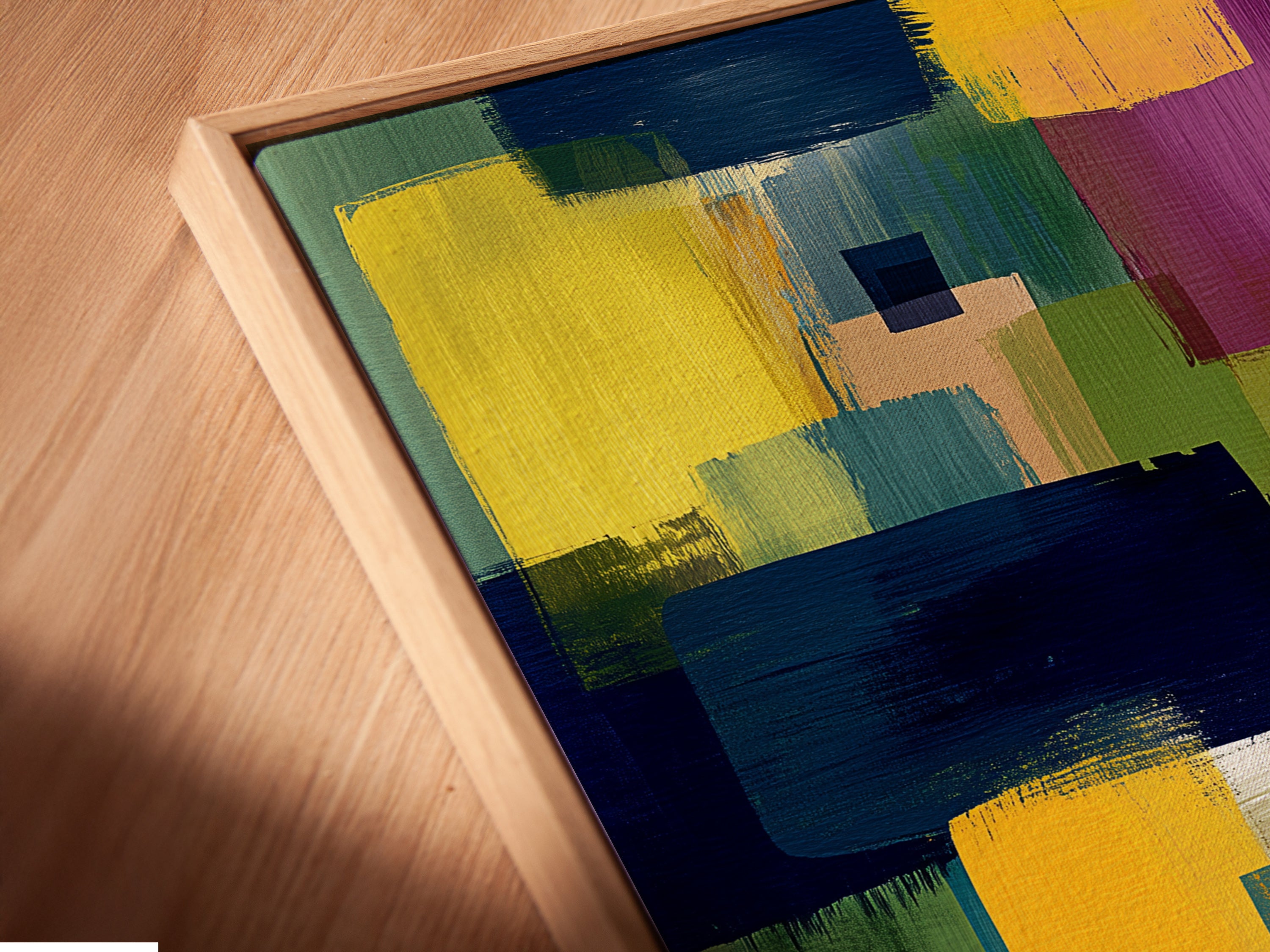 A close-up angled view of a canvas print. The artwork features an abstract colorful pattern with brushstrokes in yellow blue and purple. The canvas is mounted in a floating frame. The floating frame enhances the artwork's contemporary appeal.