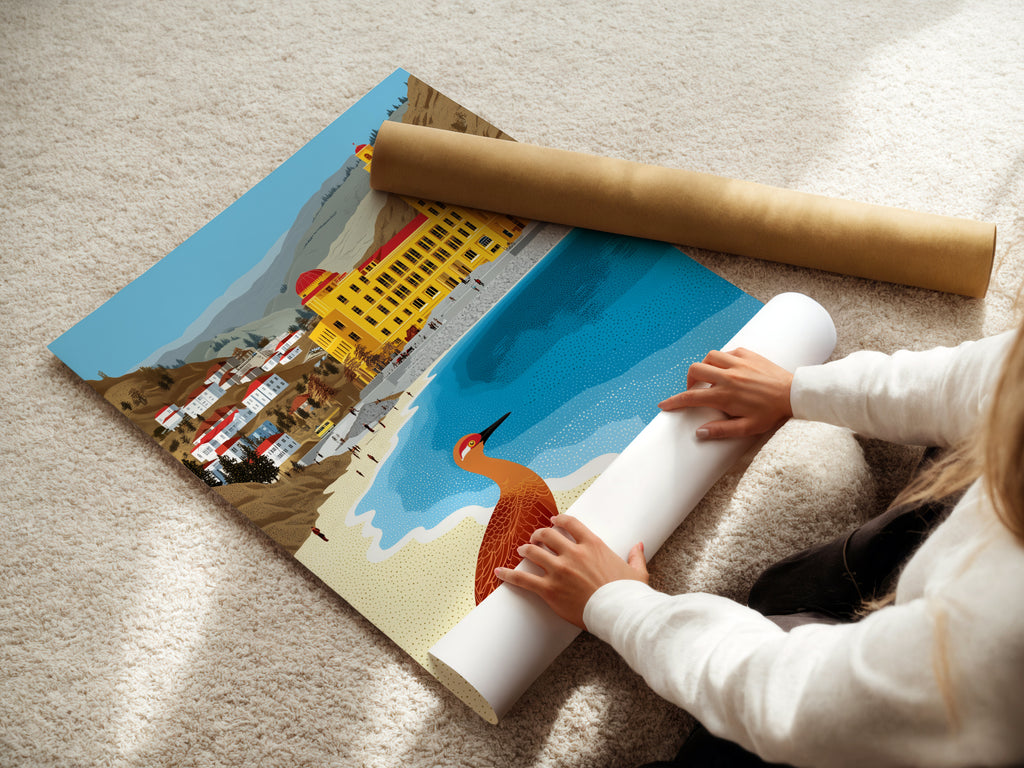 A woman carefully rolling a fine art poster paper featuring coastal artwork. Perfect for creating beach town art. The seaside decor is ideal for any room. Ochre and teal tones offer a calming aesthetic.