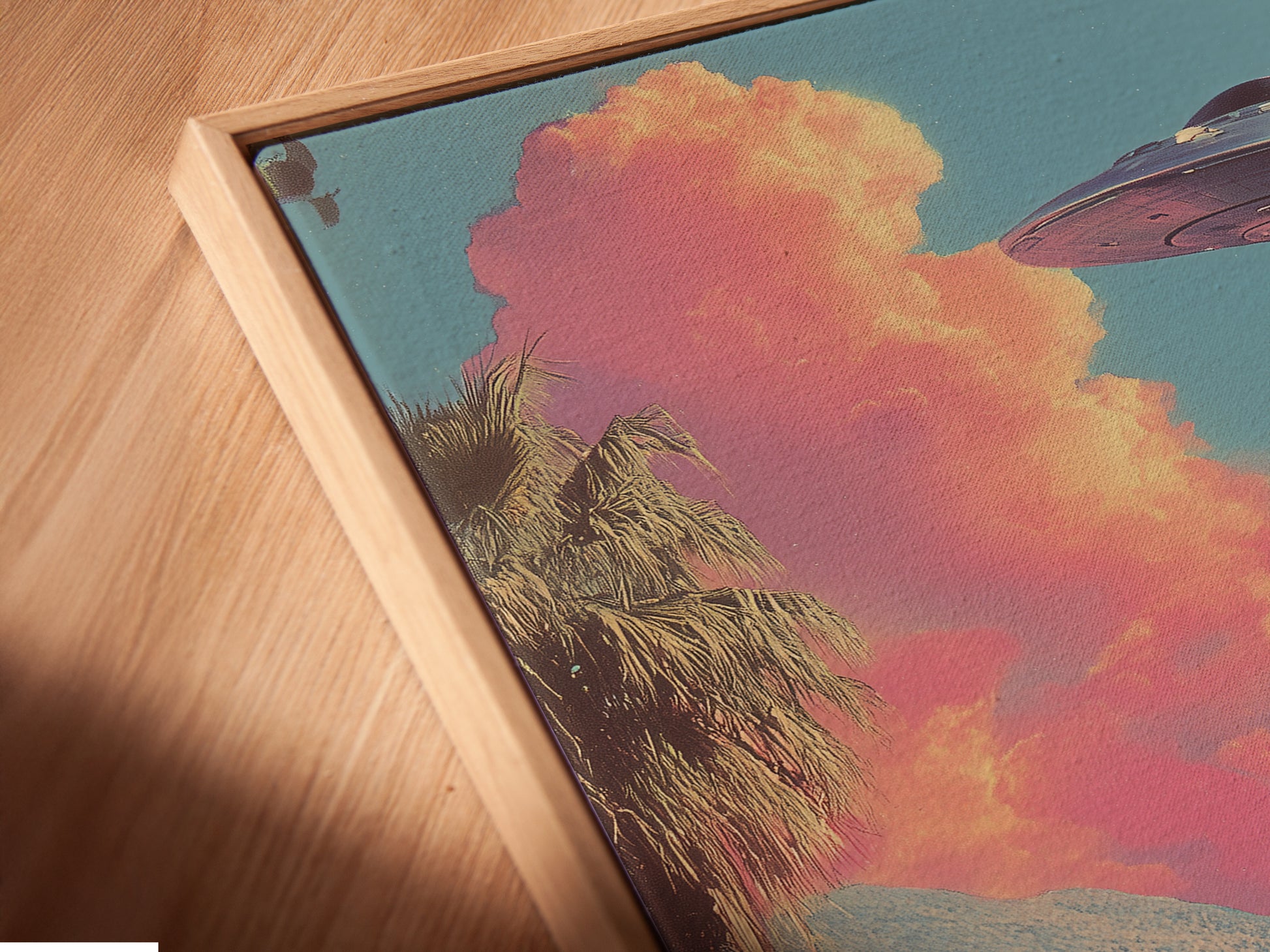 A close-up angled view of a canvas print displayed in a floating frame. The retro alien canvas print adds a touch of surreal sci-fi to the wall. The artwork enhances bedroom decor with its mid-century style. Primary color is pink. Secondary color is blue.