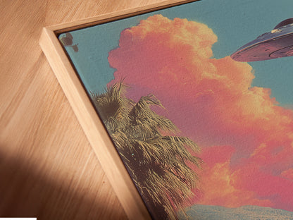 A close-up angled view of a canvas print displayed in a floating frame. The retro alien canvas print adds a touch of surreal sci-fi to the wall. The artwork enhances bedroom decor with its mid-century style. Primary color is pink. Secondary color is blue.