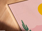 A close-up shot reveals a Desert Oasis canvas print in a floating frame. The artwork appears to float adding a modern touch. The pink and teal colors are vivid. This offers a unique and stylish way to display your art.