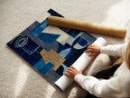 A woman carefully rolling a fine art poster paper featuring our abstract blue artwork. The modern geometric print is perfect for adding a touch of elegance to any room. Shop our high-quality fine art posters and elevate your decor now!