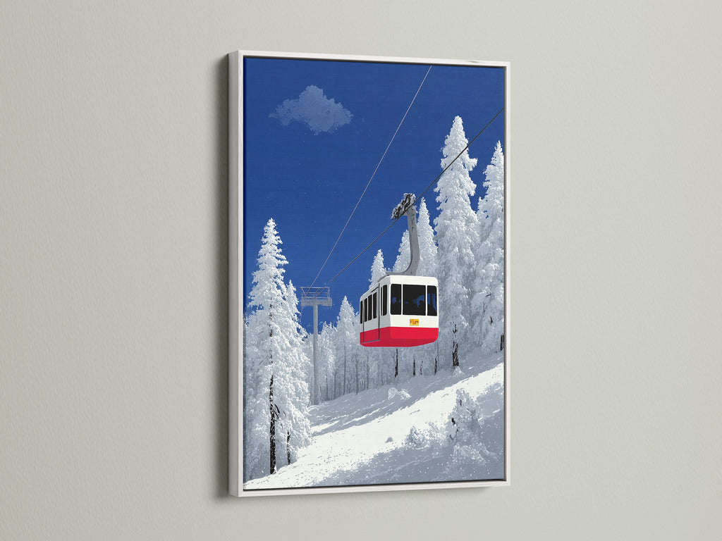 A white frame surrounds this ski lift art. This winter mountain scene is perfect for cabin decor. The alpine cable car print stands out. It's set against a snowy landscape. The white frame enhances the blue and white colors of the art. It creates a clean and modern look for your space.