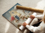 A woman carefully rolls a fine art poster paper. This high-quality paper is perfect for printing coastal artwork such as Mediterranean house canvas prints. Ideal for creating stunning Santorini-style art for bedroom or vacation home decor. Perfect for sea view prints.