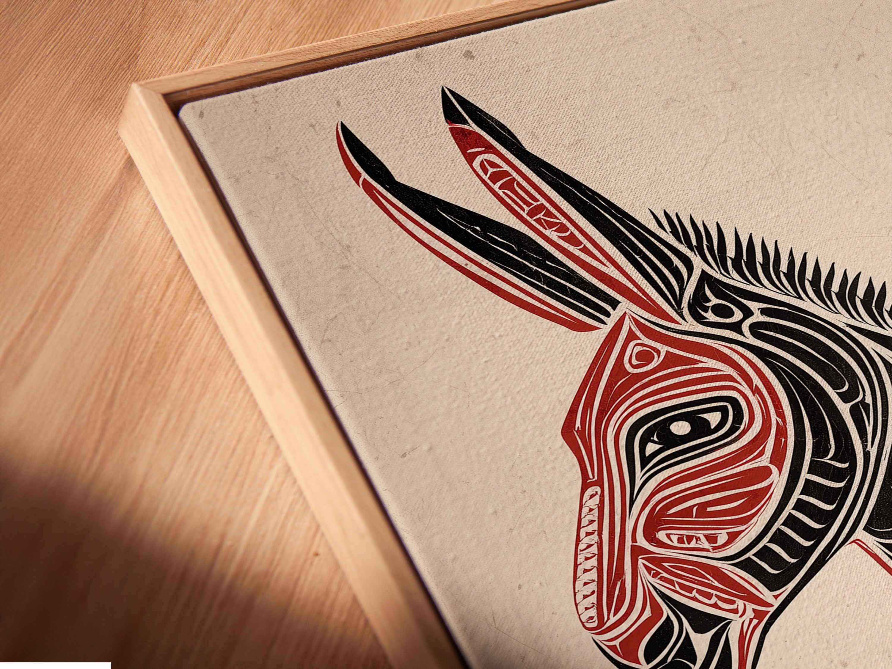 Angled close-up of a canvas print in a floating frame. The Tribal Donkey art is displayed. The floating frame enhances the artwork's contemporary appeal. This southwestern animal artwork is ready to hang. The red and black art makes a statement. Ideal for modern office wall decor.