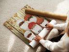 A woman is rolling a fine art poster paper. The paper features the gnome family artwork. This highlights the care in crafting high-quality art prints. Perfect for those who appreciate detailed art and craftsmanship.