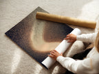 A woman carefully rolling a fine art poster paper print. This celestial art print is perfect for modern home decor. The cosmic sparkle poster adds a dreamy touch to any room. Ideal for homeowners renters and interior designers. Explore our range of abstract family artwork for your wall decor needs.