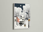 Winter Village art in a white frame is showcased. This folk art canvas is ideal for a bedroom ski chalet or cozy cafe. The snowy night art brings a Nordic style to your winter home decor. 