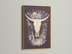 Artwork featuring a bovine skull with floral elements. It is encased in a gold frame. The gold frame adds a touch of elegance and sophistication. The artwork exudes luxury and refinement. It complements opulent interior art styles. Enhance your decor with this exquisite piece.
