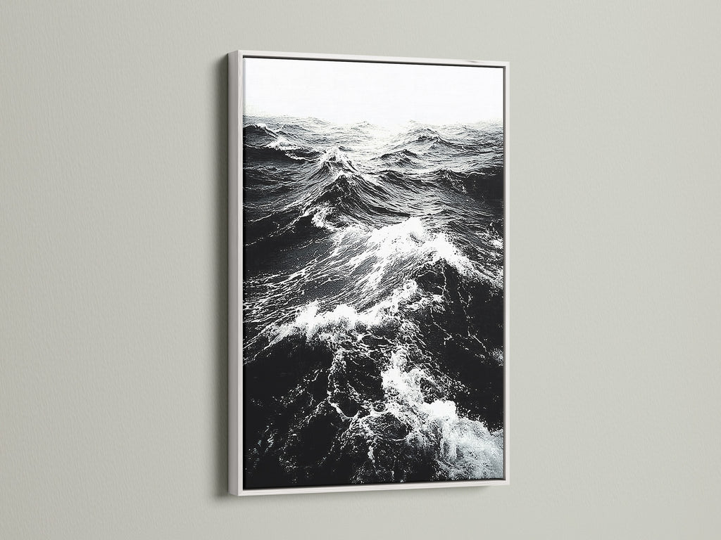 A white frame showcases black and white ocean wave artwork. The crisp white frame enhances the sea print. It provides a clean modern look for any room. Shop our coastal wall art collection today.
