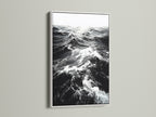 A white frame showcases black and white ocean wave artwork. The crisp white frame enhances the sea print. It provides a clean modern look for any room. Shop our coastal wall art collection today.