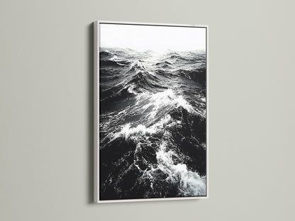 A white frame showcases black and white ocean wave artwork. The crisp white frame enhances the sea print. It provides a clean modern look for any room. Shop our coastal wall art collection today.