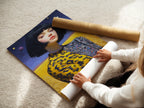A woman is carefully rolling a fine art poster paper. The paper features a surreal portrait artwork. It depicts a woman with a bob haircut. This high-quality poster paper ensures vibrant colors. It preserves the artwork's details.