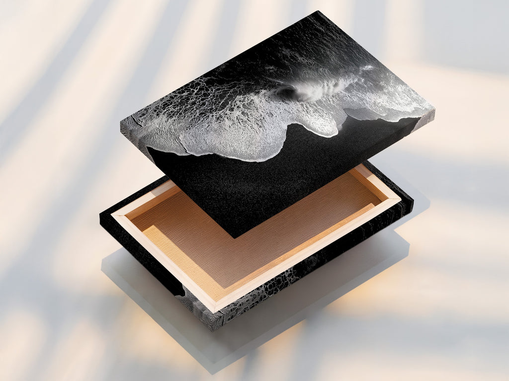 A stretched canvas print displays a captivating black and white ocean wave artwork. This piece is perfect for creating a focal point. It is perfect for minimalist decor. This beach canvas print brings coastal charm to any room. Ideal for living room wall art and office art. Add a touch of modern coastal art to your space.