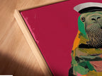 Close-up of a canvas print in a floating frame. The Walrus Sailor art print is a unique pop art piece. It is perfect for adding a touch of nautical charm to any space. The colorful animal canvas.