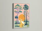 A heron artwork in a white frame hangs on a white wall. The coastal wall art depicts two herons in a peach swamp. The Florida landscape artwork complements any beach house. Perfect nature art print to brighten your living room.