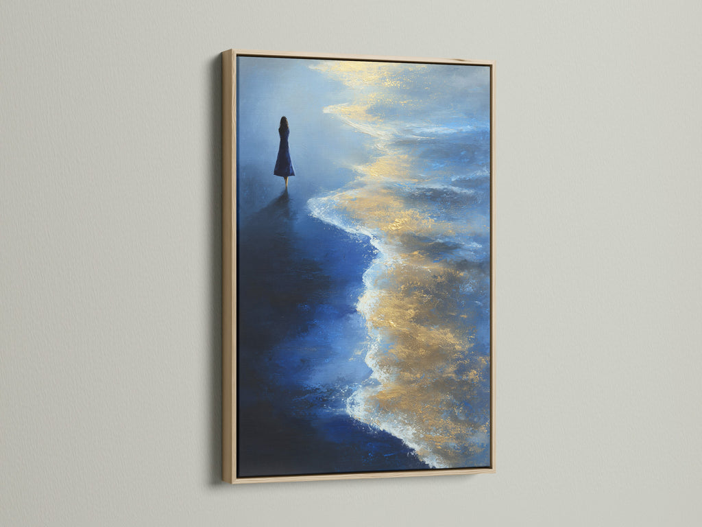 Ocean Solitude artwork with an oak frame. The art features a contemplative figure on a blue and gold beach. This seascape canvas adds a serene touch to any room. A perfect piece for meditation.