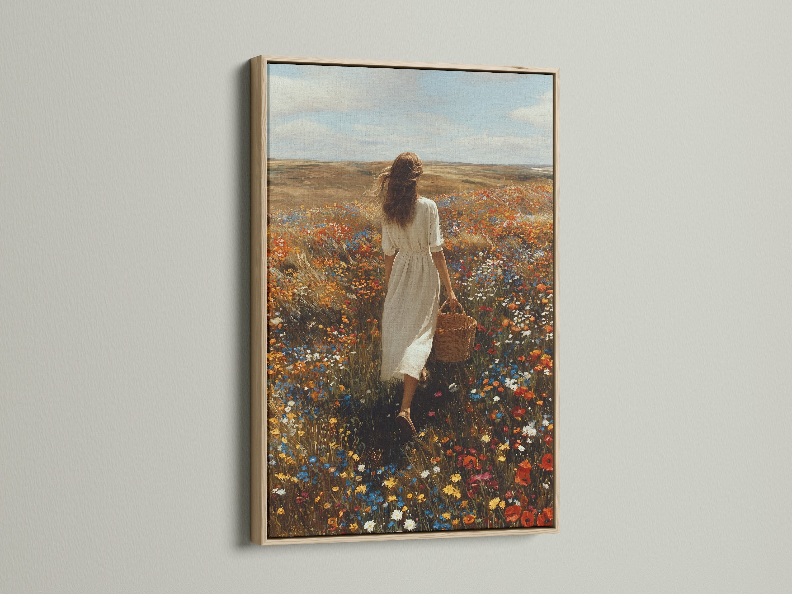Oak frame artwork on a white wall. The art shows a woman walking through a field of wildflowers. She is carrying a basket. The oak frame enhances the art. It adds a touch of nature to the interior. Find the ideal frame to display your artwork. Enhance your home decor with framed art.