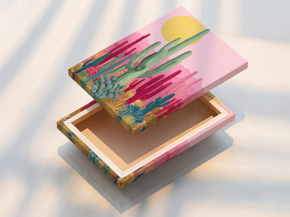 A stretched canvas print of Southwestern cactus artwork. The art features pink and teal botanical prints. This desert wall art is ready to hang. Perfect for modern minimalist or boho aesthetics. Adds color to any space.