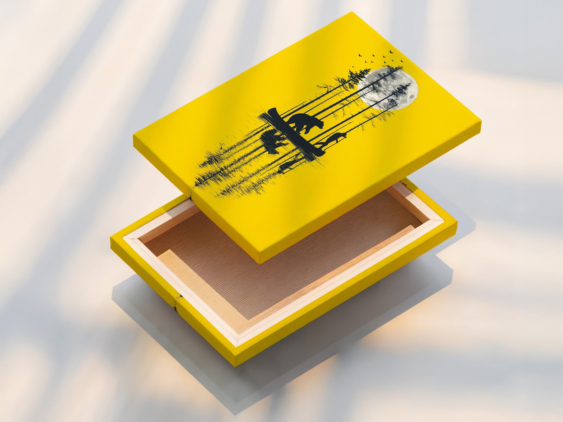 This is a stretched canvas print of the bear and canoe artwork. The yellow moon wall art is ready to hang. The nature silhouette print is stretched perfectly over a wooden frame. This cabin decor is ideal for those seeking a rustic aesthetic. The stretched canvas enhances the artwork's presence.