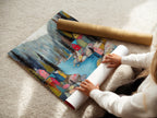 A woman carefully rolling a fine art poster paper of the Village River artwork. The poster paper ensures high-quality reproduction. It is perfect for those who appreciate detailed and vibrant prints. This option is ideal for easy framing and versatile display.