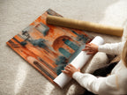 A woman is carefully rolling a fine art poster paper featuring Italian Village artwork. The artwork showcases Tuscan architecture. Its warm tones make it inviting. Perfect for adding a touch of Italy. Great travel art print.