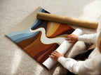 A woman is shown carefully rolling a fine art poster paper. The fine art poster paper ensures high quality prints. This abstract river artwork is available as a poster. Perfect for adding a touch of modern art to your home. Explore our range of fine art prints. Enhance your space with this elegant artwork.