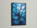 A blue flower artwork is set in a black frame. The contrast of the black frame makes the blue hues pop. This modern floral painting is ideal for a sophisticated look. It is suitable for living rooms offices and reception areas. The black frame adds a touch of elegance to this botanical artwork.