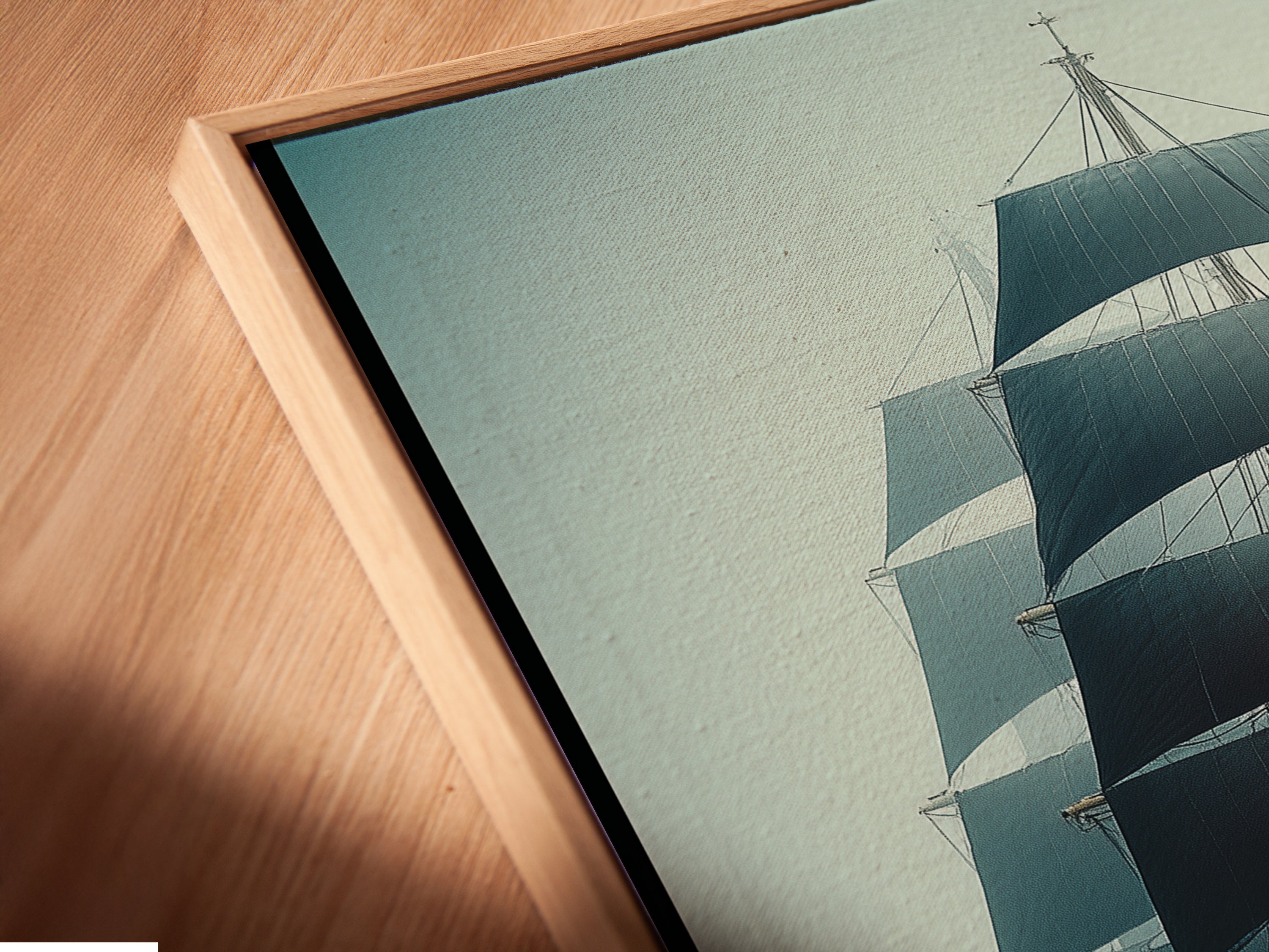 Close-up angled view of a canvas print in a floating frame. The artwork is a sailing ship. This nautical piece adds a modern touch. Perfect for living room wall art or office decor.
