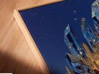 A close up of a canvas print in a floating frame. This fantasy crystal castle art is surreal. The blue crystal wall art enhances your space. A magical landscape canvas print for bedroom wall decor. Get lost in fantasy artwork today