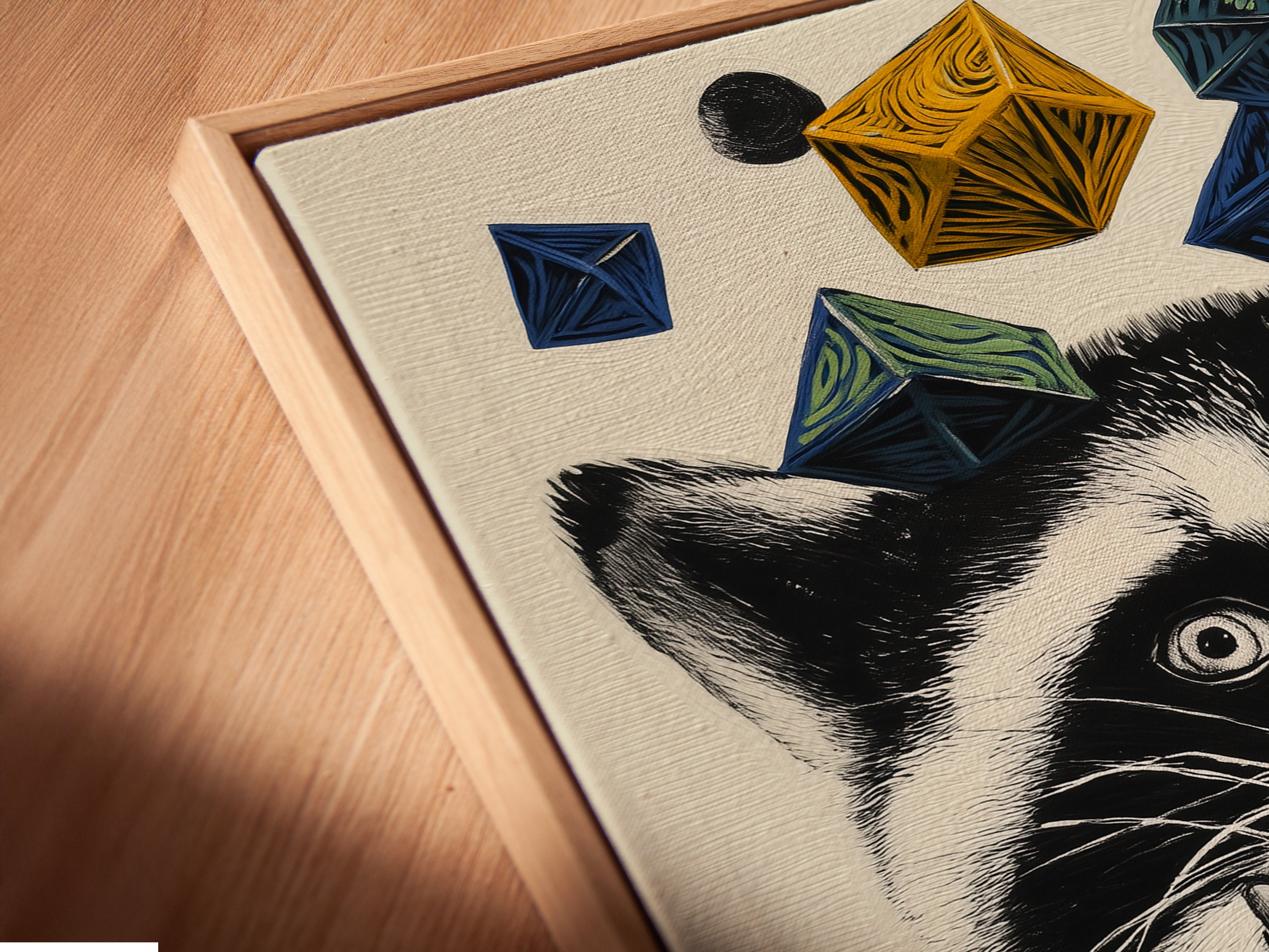 Close-up angled view of a canvas print in a floating frame. The raccoon art print features a raccoon in a mustard yellow sweater. Geometric shapes add a playful touch. This whimsical animal wall art is perfect for kids room decor. The floating frame enhances the modern aesthetic of this animal canvas print.