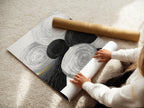 A woman is carefully rolling a fine art poster paper. The paper features an abstract geometric artwork with black and white circles. This highlights the care in preparing a high-quality art print. Ideal for wall art in modern and contemporary settings.