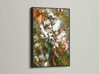 The black frame contrasts beautifully with the abstract floral artwork. The art features orange green and white tones. This combination creates a bold statement piece. This botanical canvas is perfect for a gallery or studio. Elevate your wall decor today.