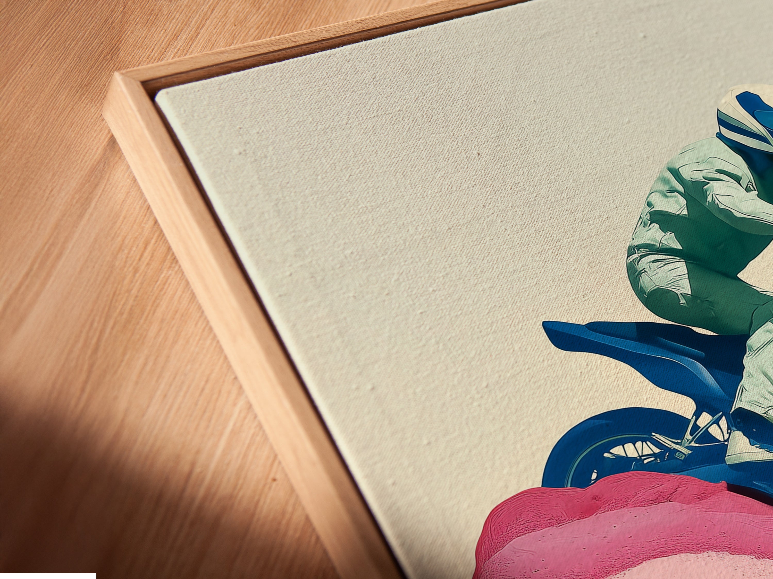 Close up angled view of a canvas print in a floating frame. The artwork features a blue motorcycle and pink accents. Perfect for garage decor. Add a vintage touch to your man cave with this retro biker wall art.