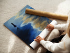 A woman carefully rolling a fine art poster paper print of Ocean Solitude. This artwork is perfect for those who appreciate elevated contemporary wall decor. Ideal for creating a serene and peaceful atmosphere at home.