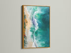 The gold frame highlights the turquoise and teal tones of the aerial beach photography. This ocean waves artwork brings a touch of luxury. It enhances any coastal or tropical themed space.