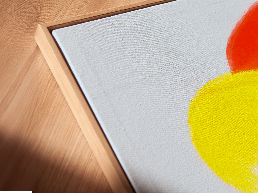 This is an angled close up of a canvas print in a floating frame. This ocean wave artwork is a vibrant surf art piece. It's a modern beach wall art for coastal decor. Enjoy a sunset wave painting. It is perfect for any room.