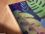 Close-up of a tropical leaves canvas print in a floating frame. The neon botanical wall art appears to float adding depth and dimension. Perfect for a modern exotic foliage poster. This unique framing enhances the artwork's vibrant colors.