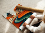 A woman is carefully rolling a fine art poster paper featuring the whimsical village artwork. This abstract landscape showcases teal and terracotta colors. This high-quality print is perfect for modern home decor. It adds a touch of European elegance to your space.