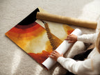 A woman rolls a fine art poster paper. The paper is for a surreal stairway artwork. Abstract mountain landscape artwork in warm earth tones is shown. Fine art posters are a great choice. Perfect for any creative space.